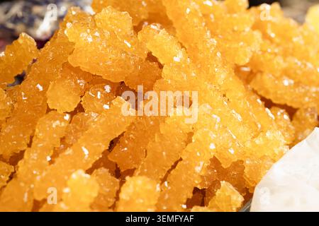 Rock candy sticks piled at Siab Bazaar in Samarkand with sparkling golden crystals. Traditional sugar confection ideal for food, travel, and cultural Stock Photo