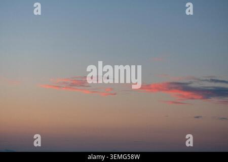 Pastel sunset sky with pink and rose lit clouds over ocean horizon at dusk, blue and peach gradient sky, Goa, India Stock Photo