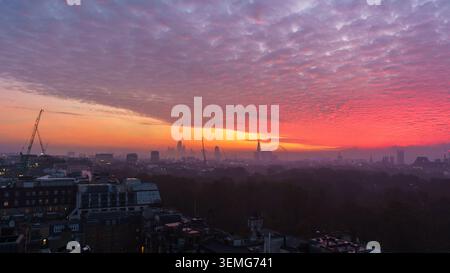 Dramatic pink and magenta sunset over London with vivid colourful clouds spreading across the sky above the distant city skyline, England, UK Stock Photo