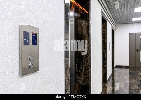 Modern elevator hallway with a Koyo panel showing "-1" and "17", marble accents, and textured white walls. Stock Photo