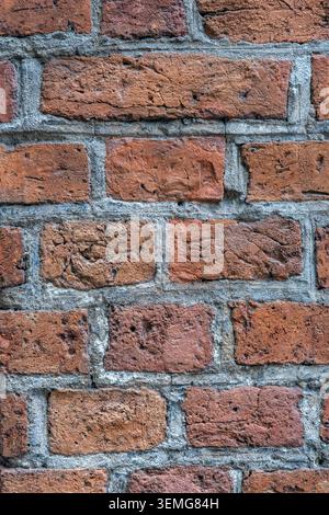 A weathered red brick wall with grey mortar is viewed at a close distance. Stock Photo