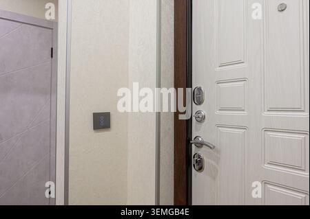 Interior view shows a white door with locks, brown trim, a light switch, and a gray patterned door in the background. Stock Photo