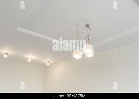 modern interior features a white ceiling with recessed lights and a cluster of globe pendant lights. The walls are also white, creating a minimalist a Stock Photo
