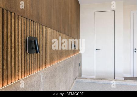 modern bedroom view showcases wooden wall panels with ambient lighting and sleek black lamps. Two white doors add to the minimalist design Stock Photo