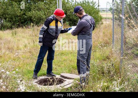 Engineers reviewing technical documentation during an inspection of an engineering structure. construction supervision, field audit, technical control Stock Photo
