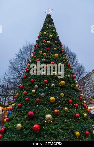 Giant decorated Christmas tree standing in a festive outdoor market Stock Photo