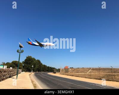 Commercial passenger aircraft operated by Jet2holidays approaching the runway, flying dramatically low above the airport perimeter road. The large Jet Stock Photo