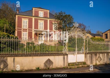 An imposing multi-story period residence stands out for its red brick facade and closed white shutters. The property is protected by an elegant and de Stock Photo