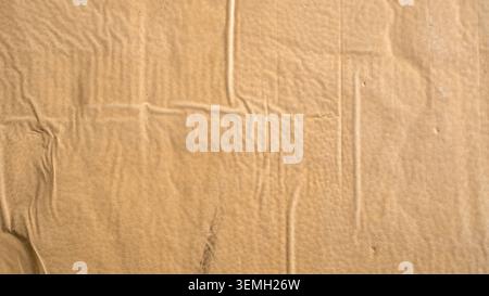 Close up of clear adhesive shipping tape melted and wrinkled onto brown cardboard box surface Stock Photo