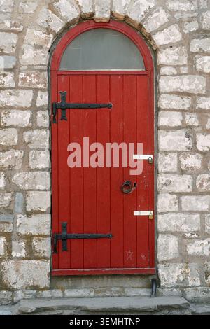 Historic Red Wooden Door with Stone Archway and Iron Hardware Stock Photo