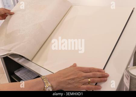 Customer Browsing Wallpaper Catalog Book in Modern Interior Design Showroom Stock Photo