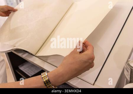 Customer Browsing Wallpaper Catalog Book in Modern Interior Design Showroom Stock Photo