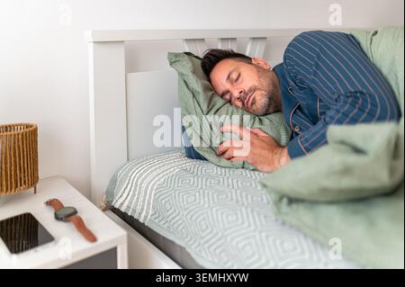 Young man sleeping peacefully on a comfortable pillow in bed, enjoying a cozy morning nap and restorative, relaxed sleep at home for wellness and quie Stock Photo