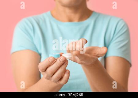Mature woman with contact lens and case on pink background Stock Photo