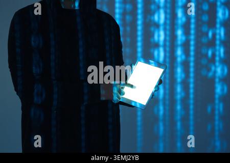 Hacker using tablet computer and projection of programming code in dark room, closeup Stock Photo