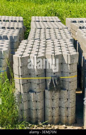 Stacked concrete paving blocks are stored outdoors, ready for use in various construction and landscaping projects. Stock Photo