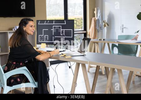 Colleagues working in design studio, Indian woman wearing saree top reviewing floor plan on monitor Stock Photo