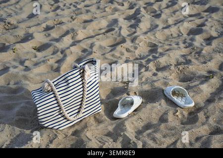 Beach bag and sandals on the beach Stock Photo