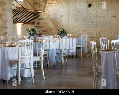 Reception room with elegantly set tables and chairs prepared for an event or wedding in France. Stock Photo