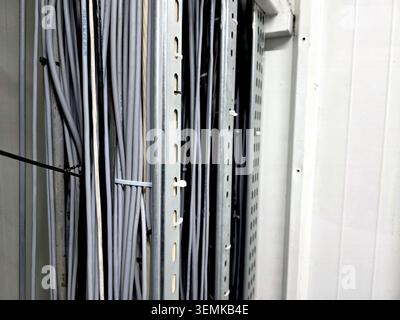 A collection of electrical cables organized in a rack inside a workshop. The cables are arranged to ensure easy access and safety during use. Stock Photo