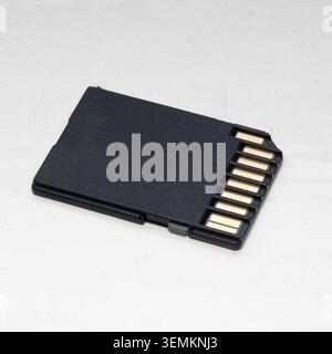 Black SD memory card with gold contacts on a white background. Stock Photo