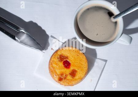 Bakery and pastry shop, culinary art and tradition of Mexico. Pineapple upside-down cake with a cherry on top, with a cup of coffee and kitchen tongs Stock Photo
