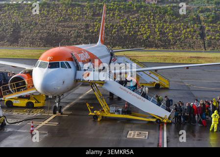 Passengers boarding an easyJet Airbus A320 airplane via Portway mobile stairs on the tarmac at Madeira Airport, Funchal, Portugal. Stock Photo