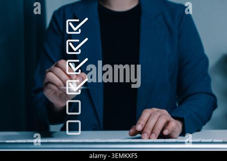 Digital checklist completion and task verification concept. Businesswoman marking check boxes on virtual list. approval, workflow progress, quality Stock Photo