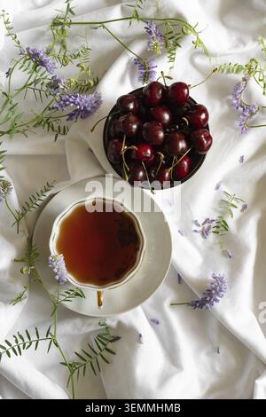 Fresh sweet cherry peel with leaves in drops of water on a stone background, view from above Stock Photo