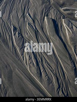 Natural pattern of water erosion in sand on beach creating flowing pattern Stock Photo