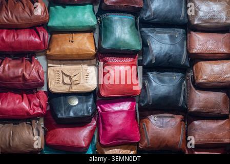 Colorful leather wallets and small bags fill a tightly packed shop display, creating rich rows of red, brown, green, black, and pink textures. Stock Photo