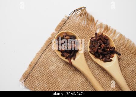 Cloves in wooden spoons on burlap cloth placed on a table Stock Photo