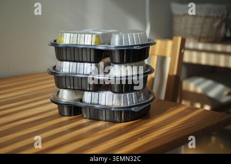 Meals stacked on a wooden table in a bright room Stock Photo