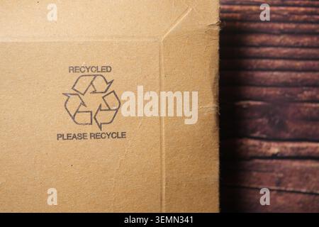 Recycling symbol on cardboard box near wooden surface Stock Photo
