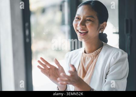 Happy businesswoman laughing and applauding during office meeting, celebrating success, positive feedback and team progress after presentation in a br Stock Photo
