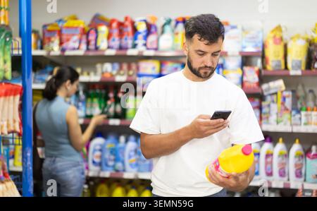 Middle-aged man scanning QR code on detergent in supermarket Stock Photo