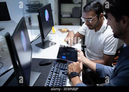 Software Developers Reviewing AI Data On Tablet In Tech Office Stock Photo