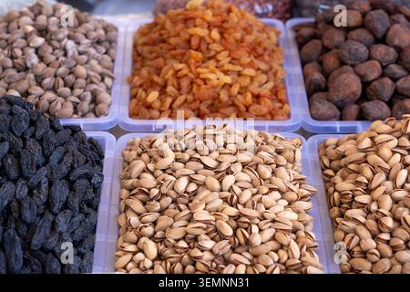 Assorted dried fruits and nuts displayed in neat plastic containers at Tashkent market. Authentic Central Asian bazaar organic food abundance concept Stock Photo