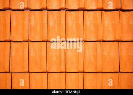 Texture of traditional orange terracotta roof tiles arranged in a perfect overlapping grid. Top view. Stock Photo