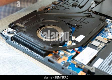 Close-up view of an opened laptop showing the cooling fan, heat pipes and internal components during repair, cleaning or maintenance Stock Photo