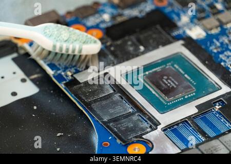 Close-up of toothbrush cleaning computer motherboard near CPU, symbolizing repair, maintenance and care of electronic hardware components Stock Photo