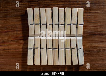 Bamboo clothespins pack on dark wooden background. Top view of a set of natural bamboo wooden clothespins attached to a card on a dark brown wooden ta Stock Photo
