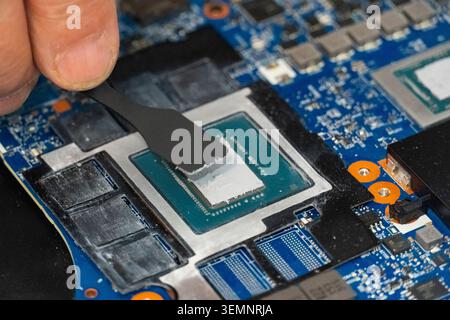 Close-up of thermal paste being applied to computer CPU with spatula tool, symbolizing repair, maintenance and cooling optimization in modern electron Stock Photo