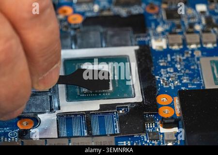 Close-up of thermal paste being applied to computer CPU with spatula tool, symbolizing repair, maintenance and cooling optimization in modern electron Stock Photo