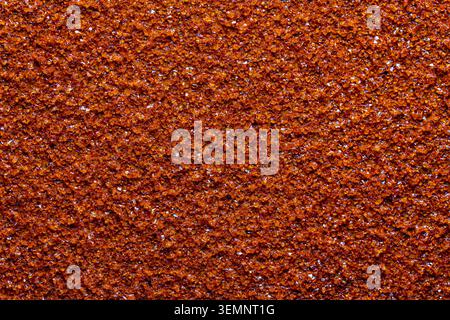 Red sandpaper texture close up background. Macro texture of abrasive sandpaper sheet surface with rough grit material creating a detailed pattern back Stock Photo
