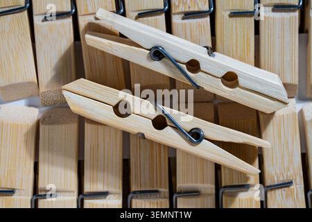 Wooden clothespins background with two wooden pegs. Close up of two light bamboo or wooden clothespins lying on top of an organized row of similar lau Stock Photo