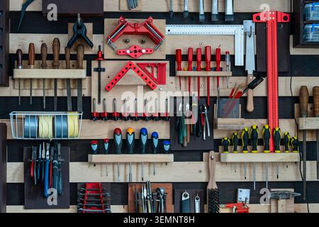 Organized workshop tool wall with hand tools on french cleat system. Full frame view of a tidy wooden pegboard wall with neatly arranged screwdrivers Stock Photo