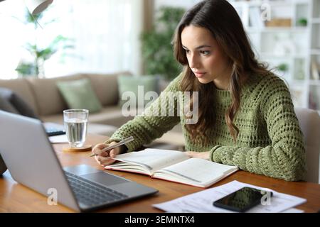 Teleworker working on a desk at home with agenda and laptop Stock Photo