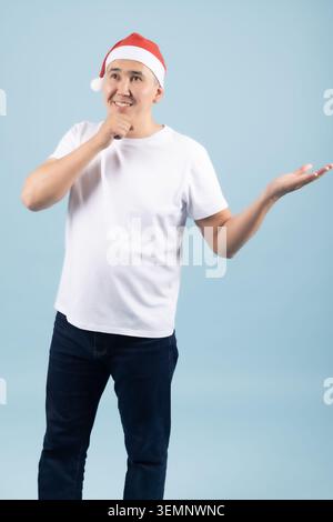 Happy man in santa hat pointing his fingers down at copy space Stock Photo