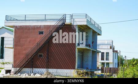 New two story building under construction with brick facade outside staircase and roof railing. Stock Photo